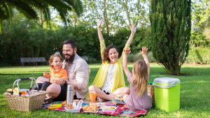 Happy family enjoying a sunny picnic with children on a blanket in a Portugal park.